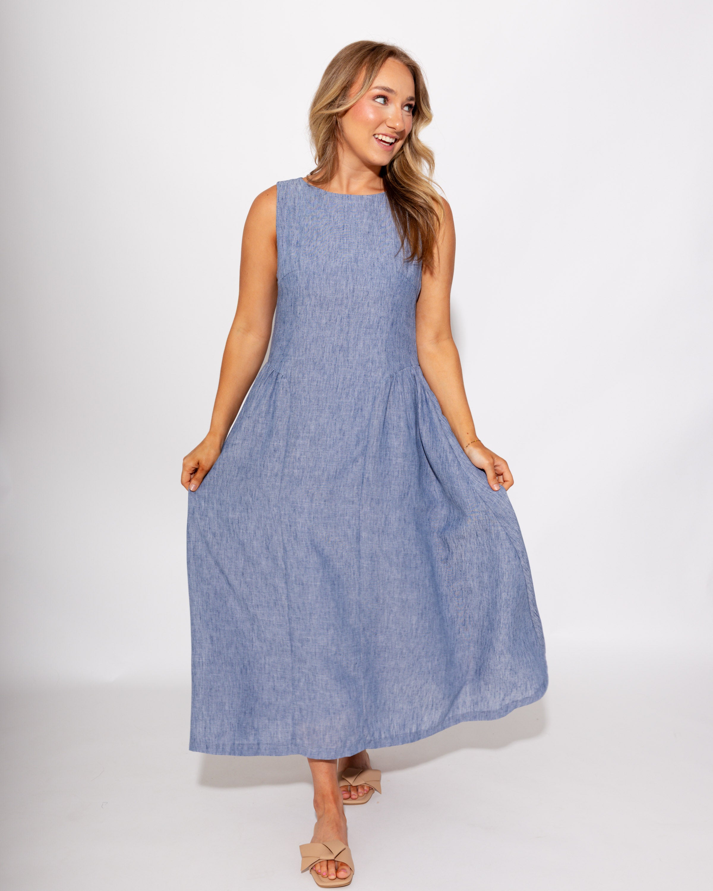 Light blue sleeveless pleated midi dress side view, A-line silhouette boutique dress at Gaudie & Co